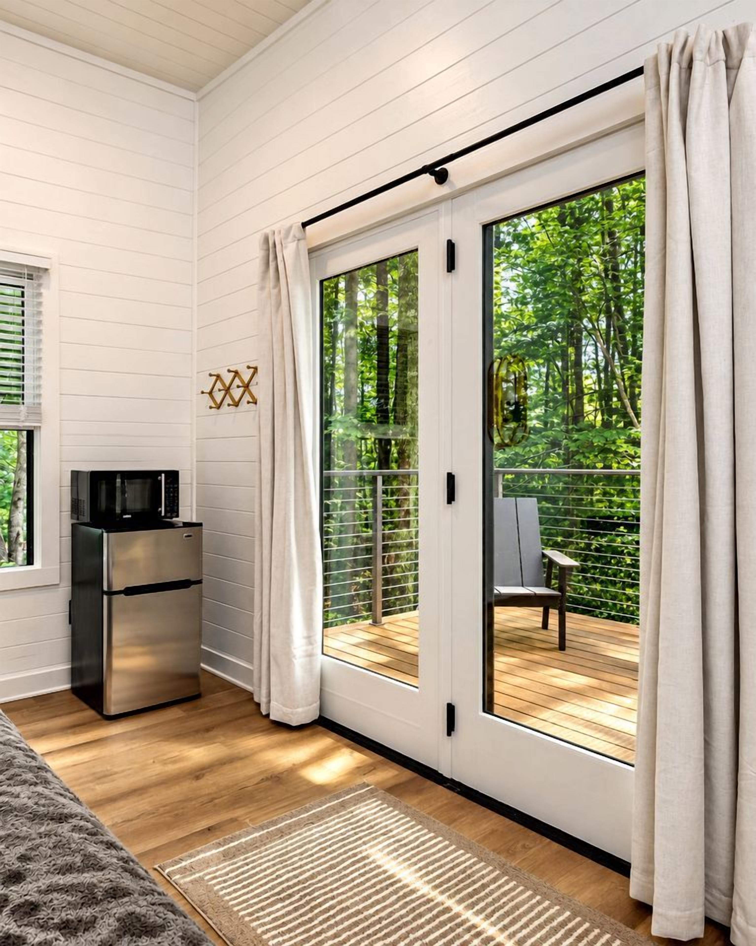 A modern room with a sliding glass door leading to an outdoor deck, a built-in microwave, and a small refrigerator.