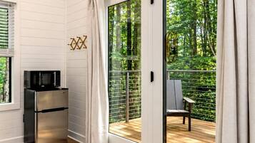A modern room with a sliding glass door leading to an outdoor deck, a built-in microwave, and a small refrigerator.