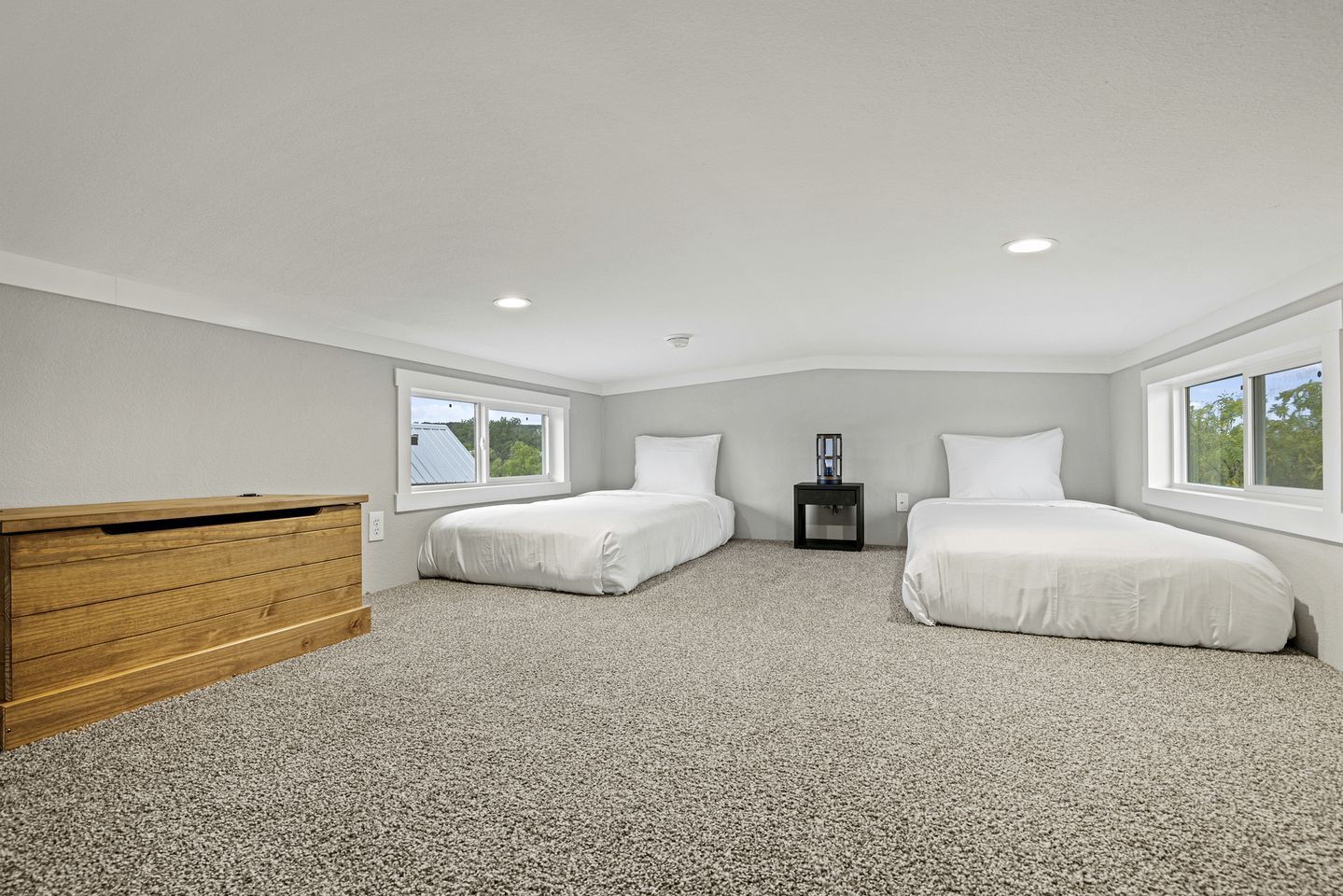 A bedroom with two beds, a wooden dresser, a nightstand, and a window.