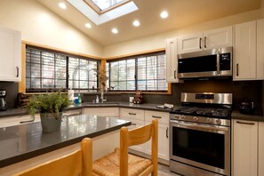 A modern kitchen with a central island, stainless steel appliances, and large windows. - Wonderful Cabin Nestled Amidst Trees with Foosball and Hot-tub in Big Bear Lake, California (Big Bear Lake)