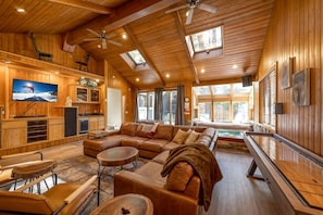 A cozy cabin interior with a large wooden ceiling, a fireplace, a television, and a pool area. - Wonderful Cabin Nestled Amidst Trees with Foosball and Hot-tub in Big Bear Lake, California (Big Bear Lake)