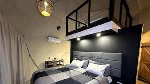 Een moderne slaapkamer met een bed, nachtkastjes en een hanglamp.