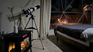 A cozy room with a bed, a telescope, and a fireplace. - Impressive Secluded Dome with Barbecue and Fire Pit in Kanab, Utah (Kanab)