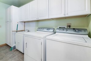 A laundry room with white cabinets and two front-loading washing machines. - Comfy Cabin with Outdoor Living Space with Spa in Big Bear Lake (Big Bear Lake)