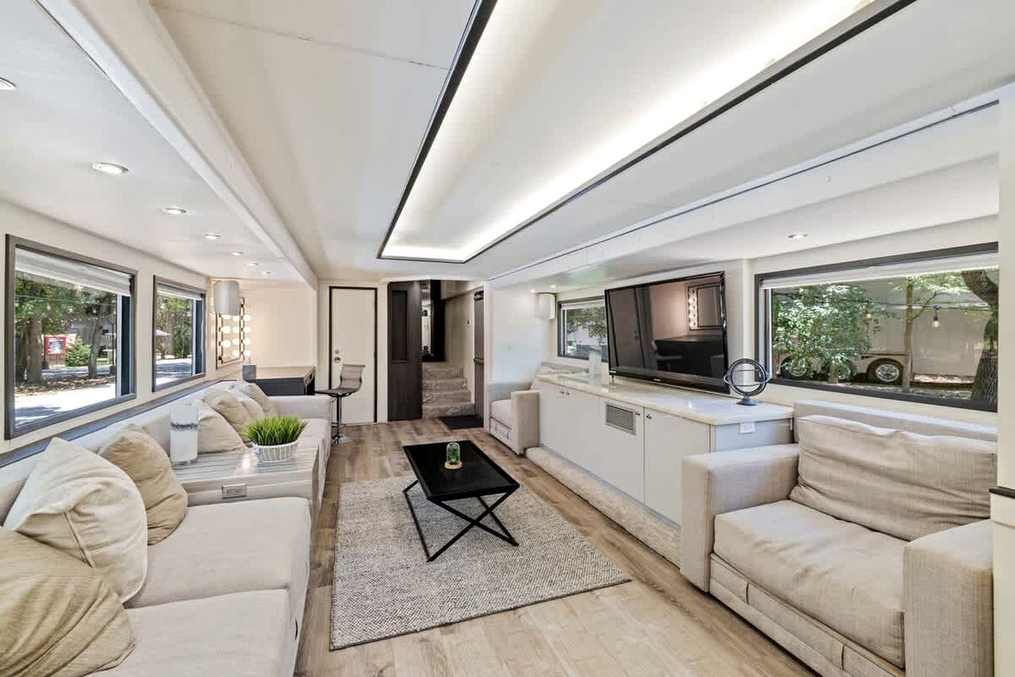 A modern interior with a sofa, a coffee table, and a kitchen area with a TV.