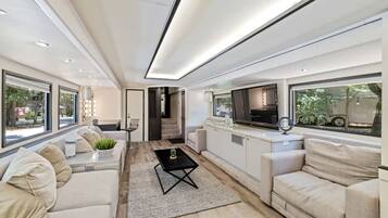 A modern interior with a sofa, a coffee table, and a kitchen area with a TV.