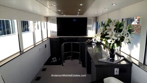 Un intérieur moderne avec un téléviseur à écran plat, un coin salon et un vase de fleurs.