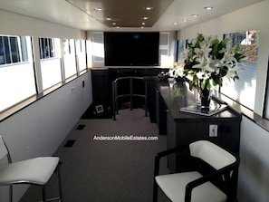 Un interior moderno con televisor de pantalla plana, zona de estar y un jarrón con flores.