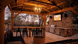Une terrasse extérieure dotée d’une pergola en bois, d’un espace salon, d’un bar et d’une cuisine extérieure.
