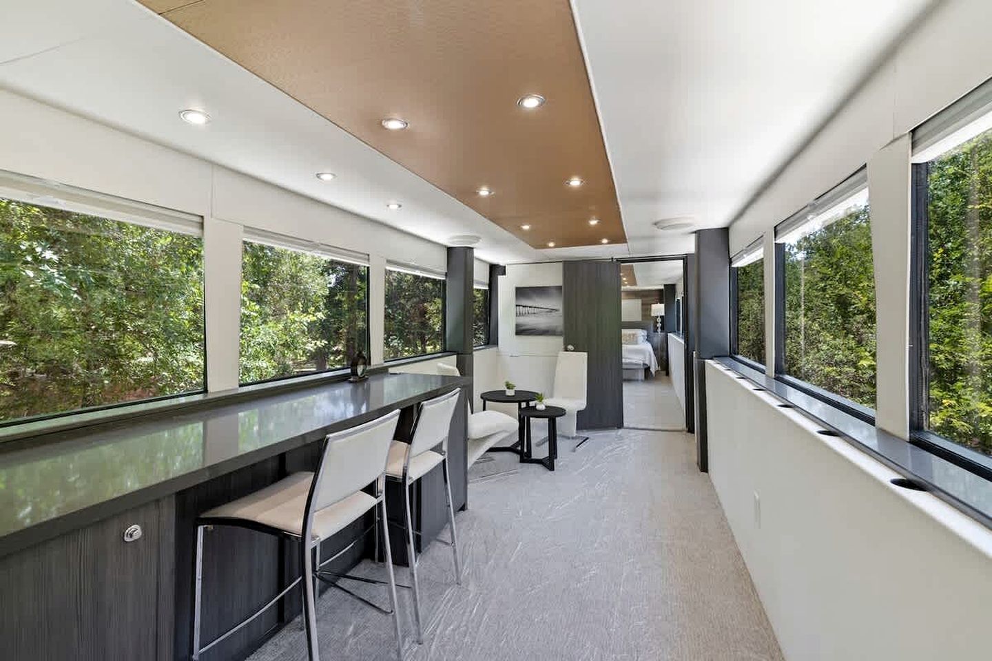 Un intérieur moderne avec un espace bar, des sièges et de grandes fenêtres donnant sur un paysage verdoyant.