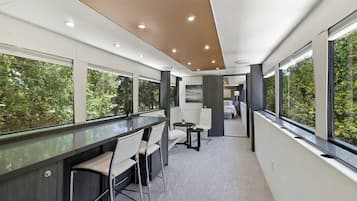 Un intérieur moderne avec un espace bar, des sièges et de grandes fenêtres donnant sur un paysage verdoyant.