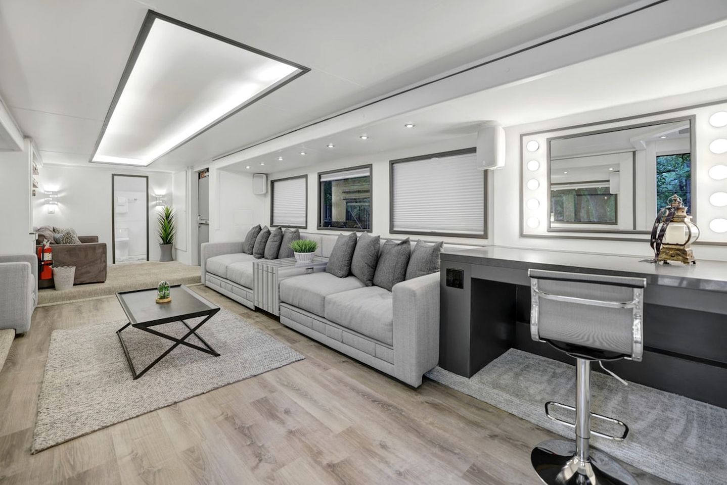 A modern living room with a grey sofa, a coffee table, and a bar area with a stool.
