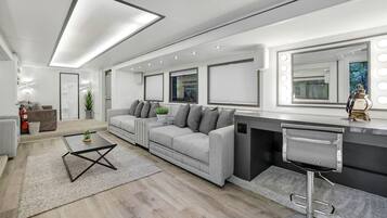 A modern living room with a grey sofa, a coffee table, and a bar area with a stool.