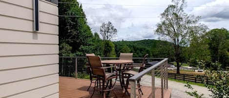 A deck with outdoor furniture, a railing, and a view of a rural landscape.