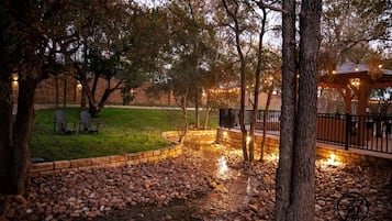A landscaped outdoor area with a stone pathway, seating, and a gazebo.