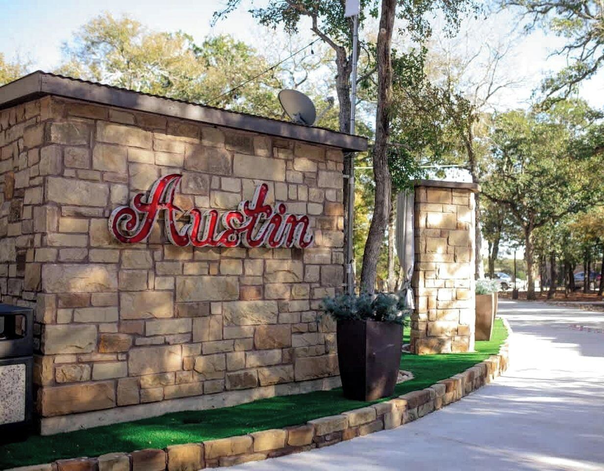 A stone wall with the word 'Austin' in red lettering, a satellite dish, and a planter with green foliage.