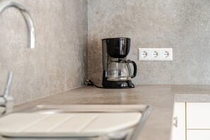 A kitchen with a coffee maker, a sink, and a countertop. - Apartment 'Kirschblüte' with Mountain View, Shared Garden and Wi-Fi (Oberkirch)