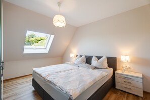 A bedroom with a bed, bedside tables, a window with a view, and a ceiling light. - Apartment 'Kirschblüte' with Mountain View, Shared Garden and Wi-Fi (Oberkirch)