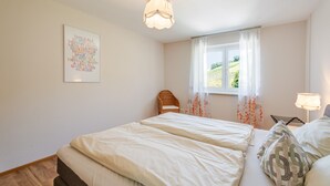 Una camera da letto con un letto, una finestra con tende, una lampada a parete e un quadro incorniciato.