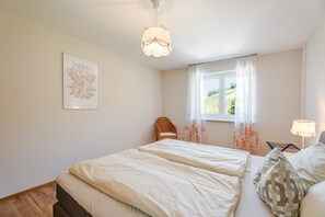 A bedroom with a bed, a window with curtains, a wall-mounted light fixture, and a framed picture. - Apartment 'Ferienwohnung Rebblüte' with Mountain View, Shared Garden and Wi-Fi (Oberkirch)