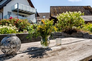 A wooden table with a glass vase containing flowers, a metal lantern, and a glass candle holder. - Apartment 'Ferienwohnung Rebblüte' with Mountain View, Shared Garden and Wi-Fi (Oberkirch)