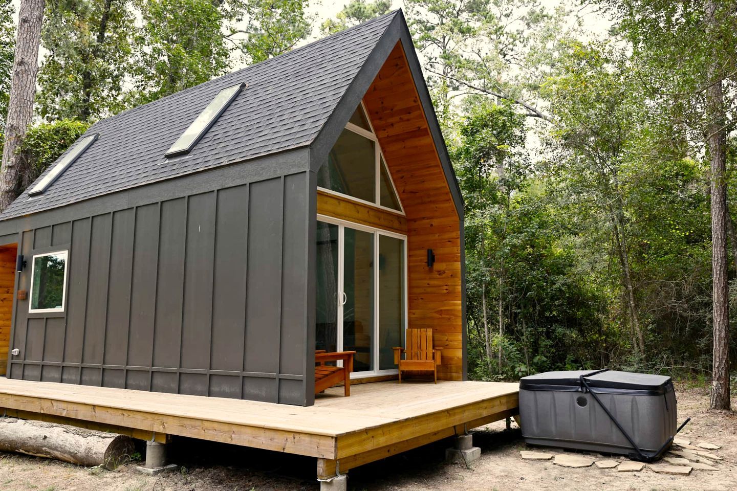 Une cabane avec un toit en pente, une terrasse et un jacuzzi.