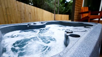 A hot tub with jets, a wooden fence, and a wooden structure in the background.