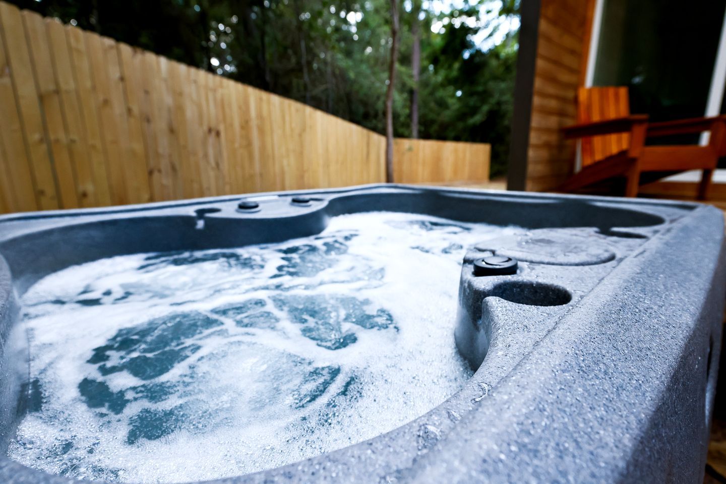 Ein Whirlpool mit Düsen, ein Holzzaun und eine Holzbeschreibung im Hintergrund.