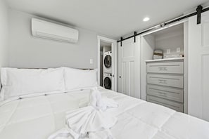 Ein Hotelzimmer mit einem Bett, einer weißen Klimaanlage, einer Waschmaschine und einer Schiebetür zum Kleiderschrank.