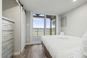 A bedroom with a bed, a wardrobe, and a balcony with a view of the outdoors. - Pet Friendly Cabin with Fire Pit in Fredericksburg, Texas (Fredericksburg)