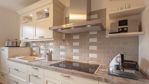 A modern kitchen with white cabinetry, a built-in stove, and a microwave. - Modern vacation home with plenty of space to relax - Haus Eleganza (Glowe)