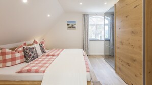 Un dormitorio con cama, almohadas, una ventana y un panel de madera.