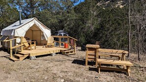 Une tente dotée d’une terrasse en bois, d’un banc et d’une échelle.
