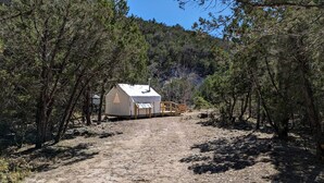 A single-story cabin with a pitched roof, surrounded by dense forest.