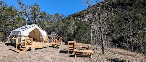 A tent with a wooden deck, a picnic table, and a chair.