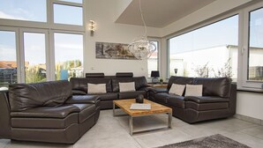 Uma sala de estar moderna com um sofá seccional, uma mesa de centro de madeira e uma grande janela com vista para o exterior.