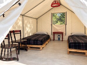 A tent with two beds, a table, and chairs.