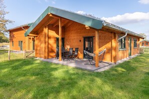 Eine Holzhütte mit überdachter Veranda, Sitzgelegenheit im Freien und einer Hängematte.