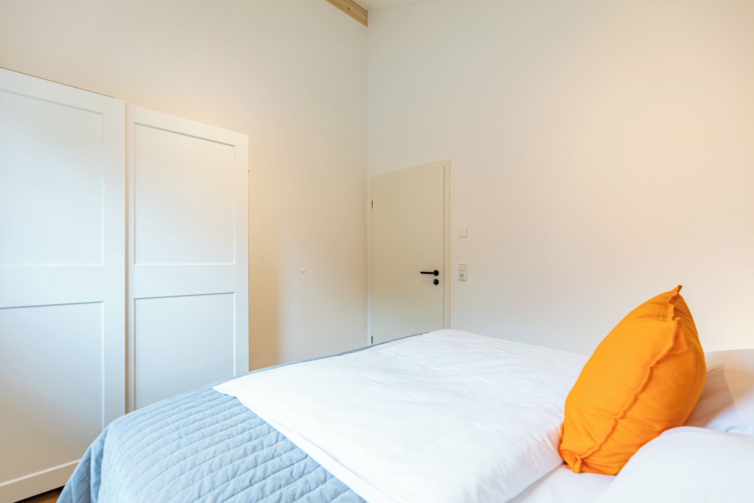 Un dormitorio con cama, puerta y pared.