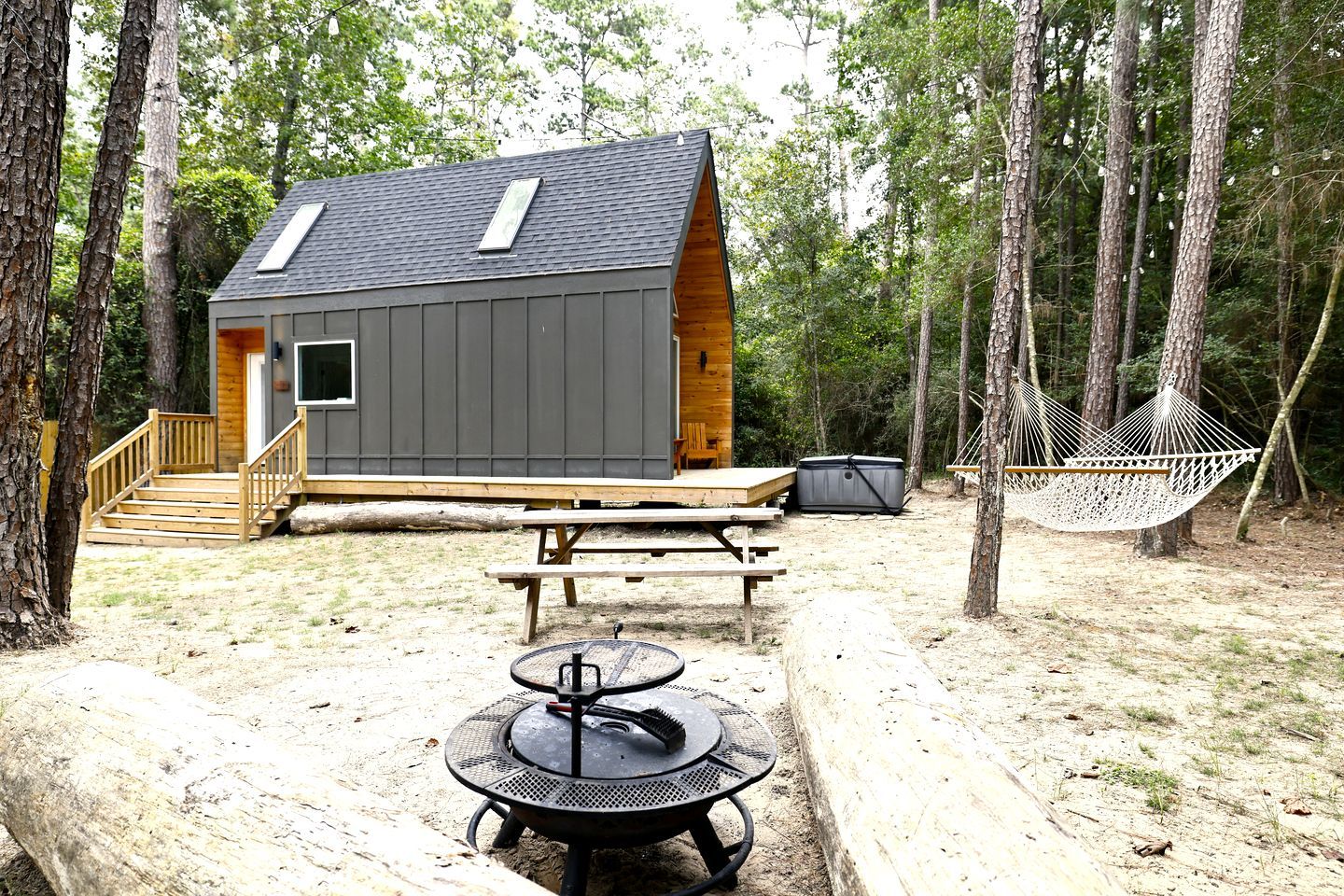 A cabin with a deck, a picnic table, a hammock, and a grill.