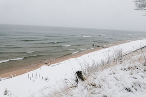 A beach with snow-covered sand and a wooden jetty.