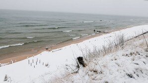 A beach with snow-covered sand and a wooden jetty. - Family Friendly Cabin Rental in Muskegon for Relaxing Getaways to Lake Michigan (Muskegon)