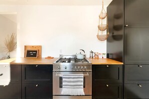 A kitchen with a stainless steel stove, black cabinets, and a wooden countertop.