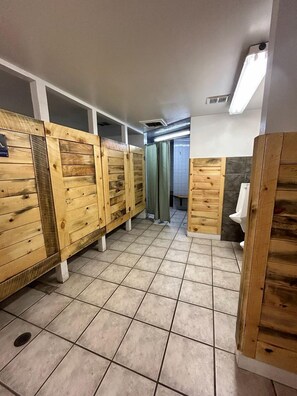 Un lavabo públic amb separadors de fusta, sòl de rajola i un vàter visible.