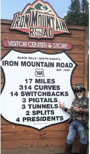 A sign for Iron Mountain Road with details like 17 miles, 314 curves, and 14 switchbacks. - Comfortable Cabin Perfect for Couples Exploring the Outdoors in Sturgis, South Dakota (Sturgis)