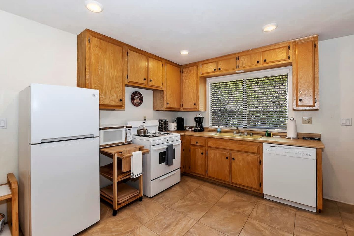 A kitchen with wooden cabinets, a white refrigerator, a microwave, a stove, and a dishwasher.