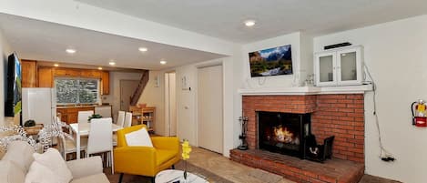 A living room with a fireplace, a dining area, and a kitchen.