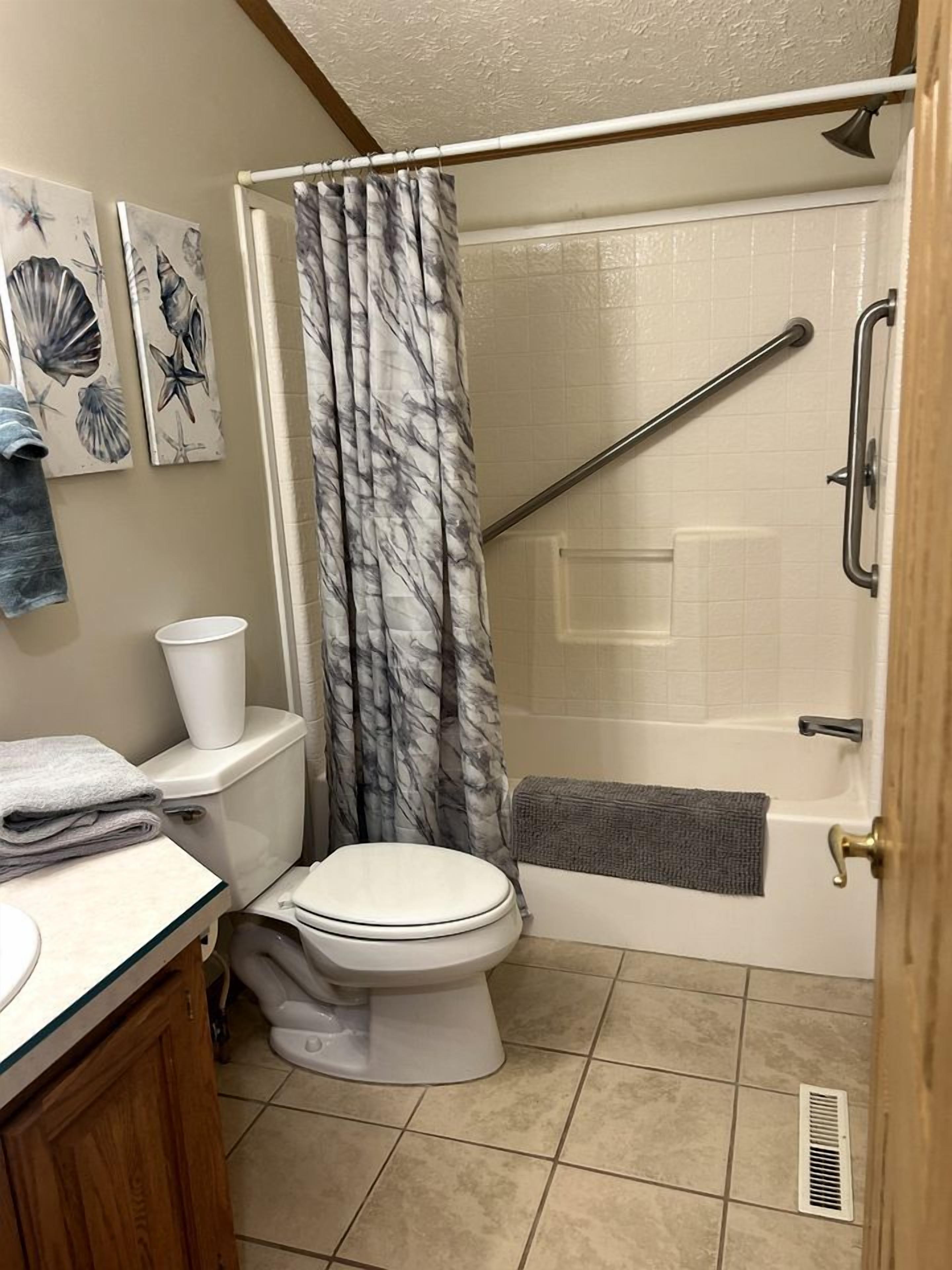 A bathroom with a toilet, shower, and sink.