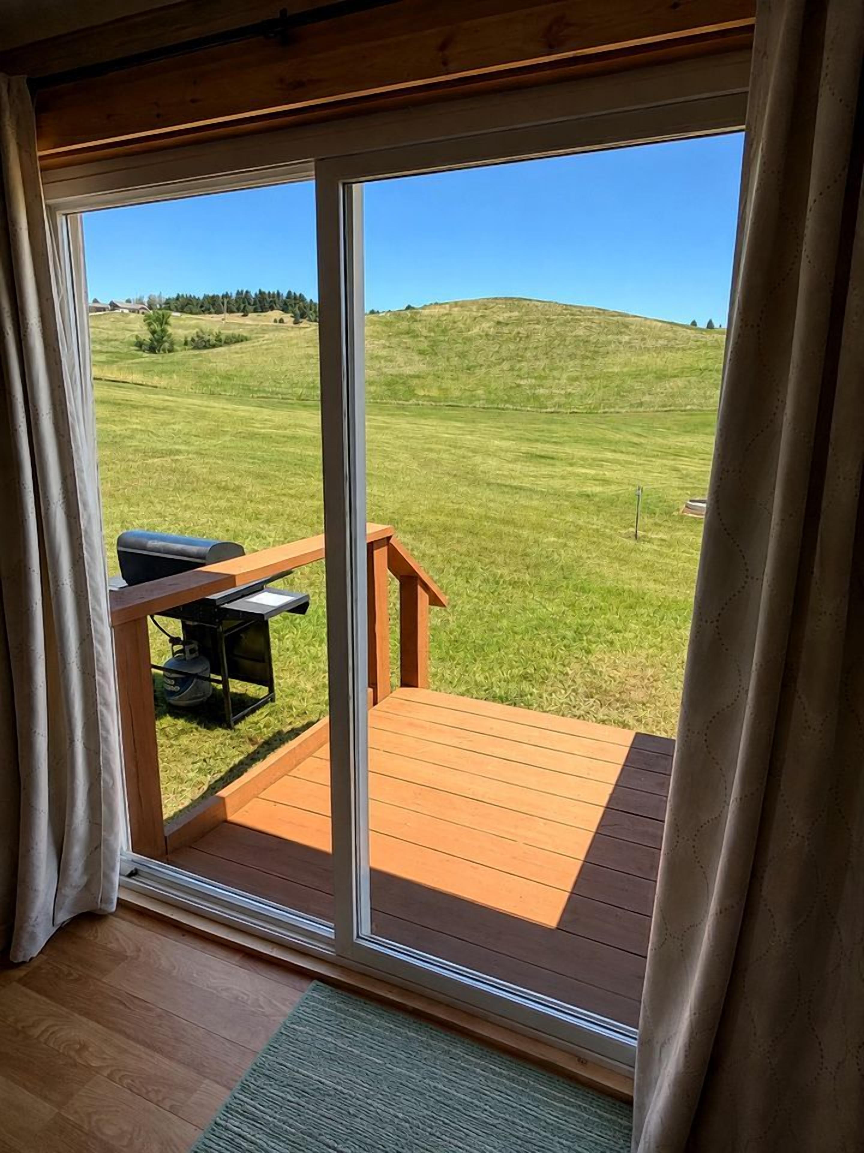 A room with a sliding glass door leading to an outdoor deck with a barbecue grill.