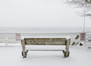 Un banco de madera cubierto de nieve con señales de precaución.